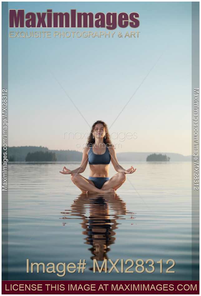 Woman practicing meditation sitting on platform in the water