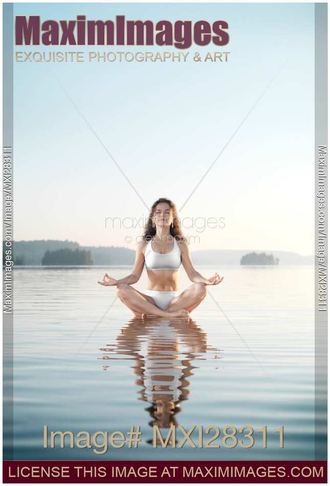 Woman practicing morning sunrise meditation on the water