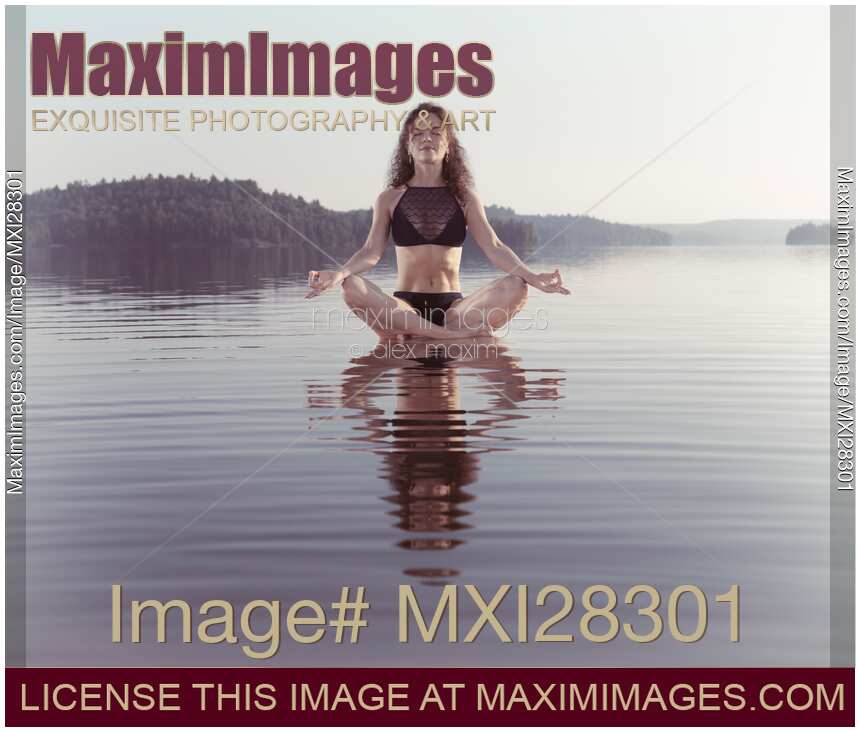 Woman practicing still sitting meditating on platform in the water