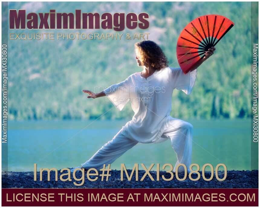 Woman practicing Tai Chi with a fan in sunrise in the nature