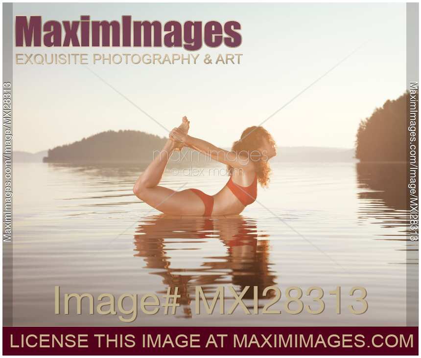 Woman practicing yoga on platform in the water Bow Dhanurasana pose