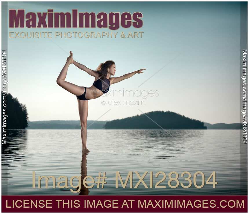 Woman practicing yoga on platform in the water doing Dancer pose