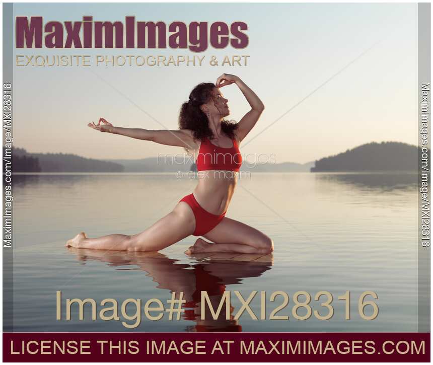 Woman practicing yoga on platform in the water doing Pigeon pose variation
