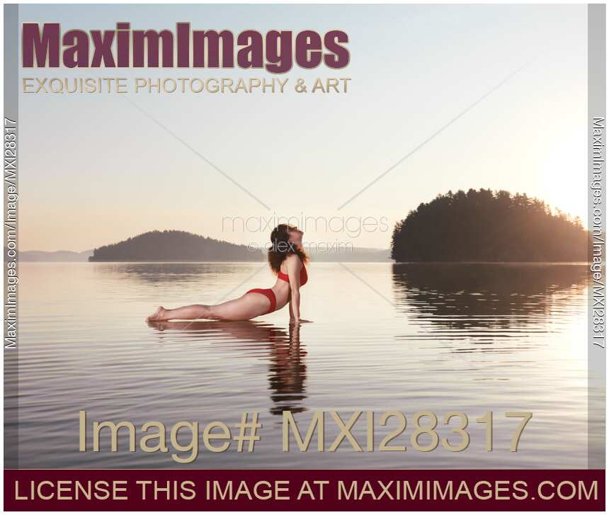 Woman practicing yoga on platform in the water Upward Facing Dog pose