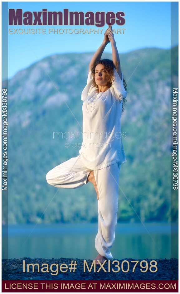 Woman practicing yoga Vrksasana standing tree pose at sunrise in the nature