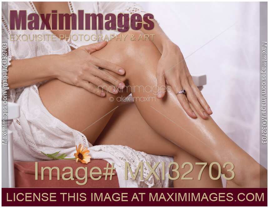 Woman rubbing body cream on her legs and calves with shiny healthy skin