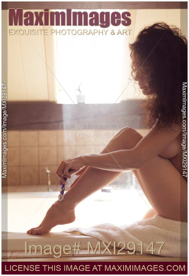 Woman shaving her legs with a razor in bathroom