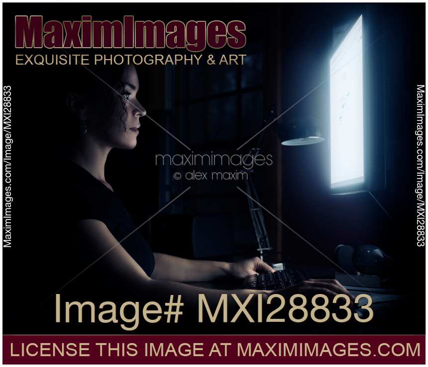 Woman sitting in dark in front of a computer screen