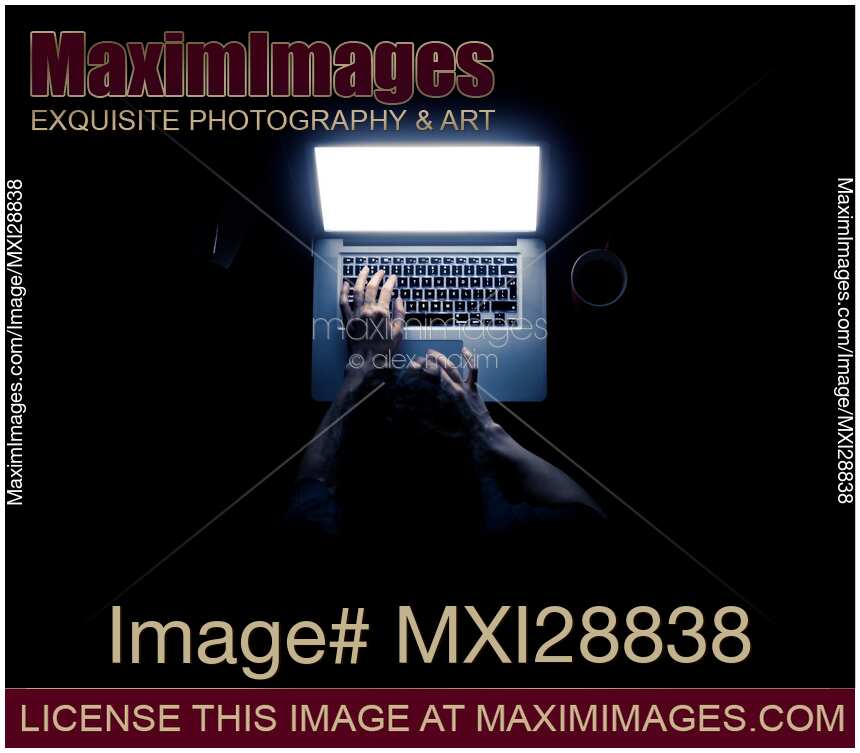 Woman sitting in light of laptop screen at a desk