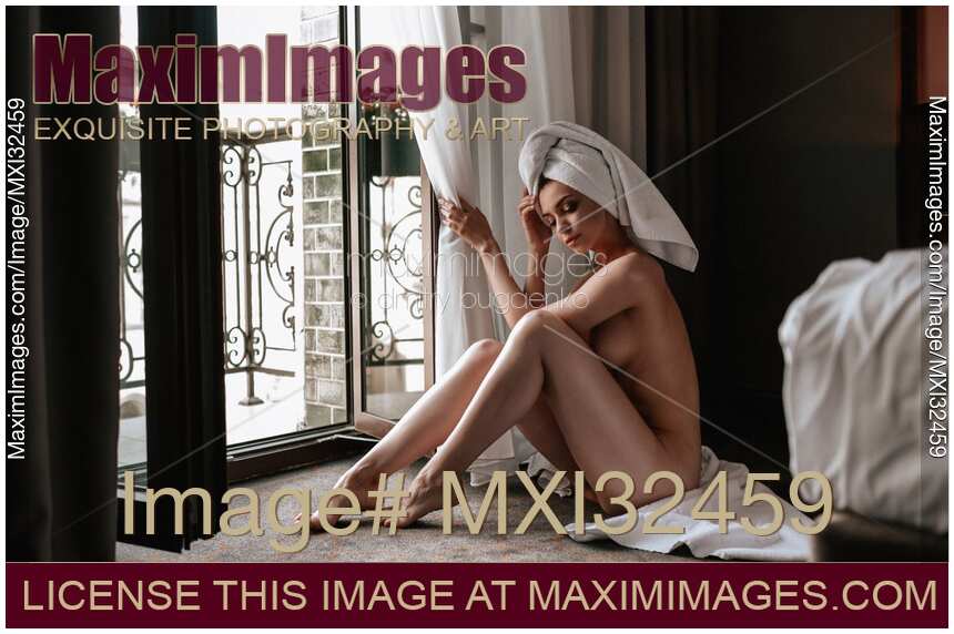 Woman sitting naked on the floor by an open balcony door after a shower