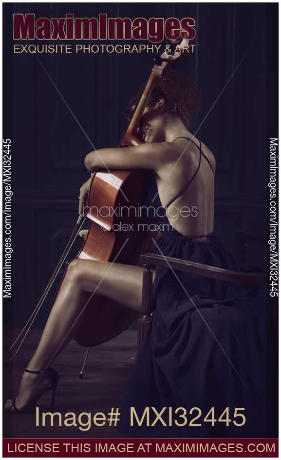 Woman sitting thoughtfully with her arms around a cello in elegant dress revealing her sexy legs and back