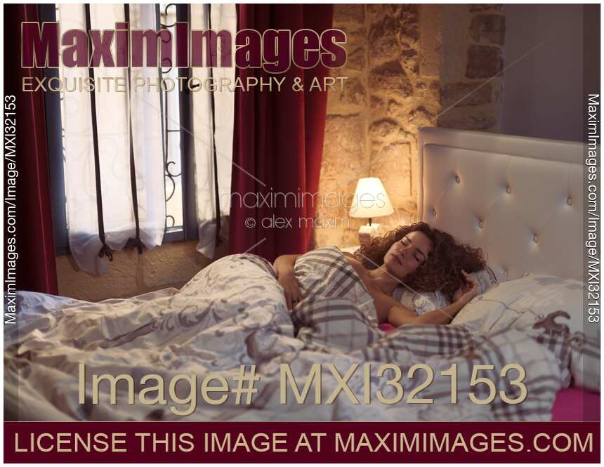 Woman sleeping in bed in the morning covered with a blanket with a night light on