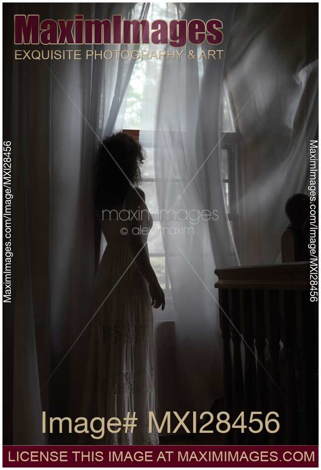 Woman standing at window in dark room