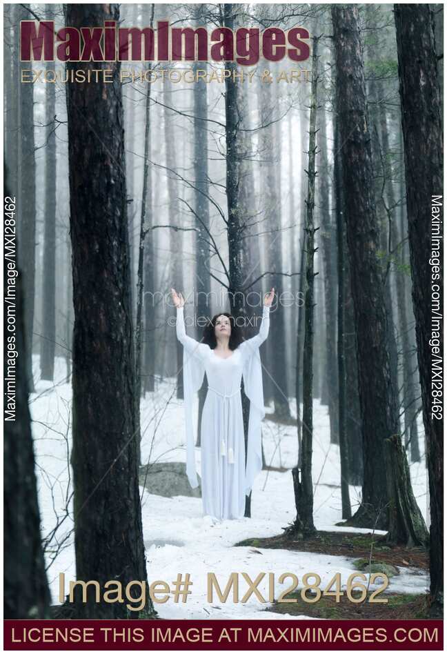 Woman standing in a forest with her arms raised