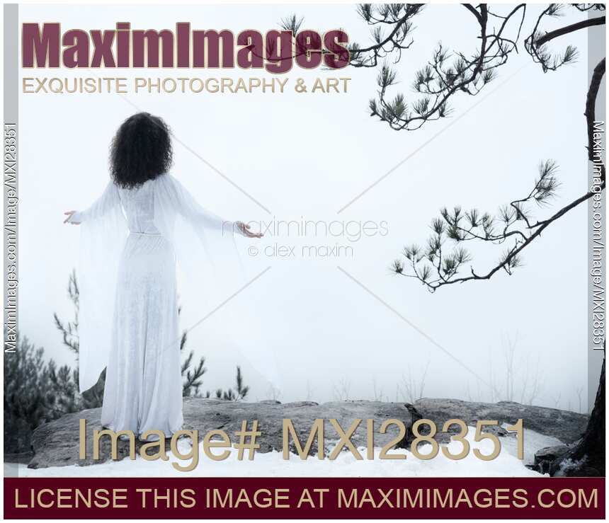 Woman standing on a cliff with spread hands embracing the world