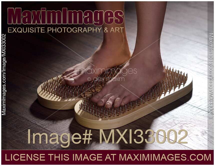 Woman standing on Sadhu Board Yogic board of nails with bare feet