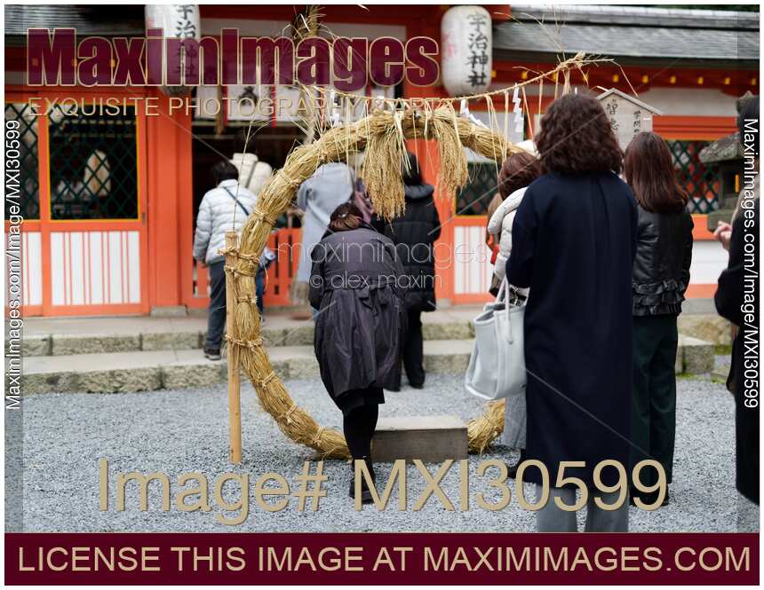 Woman stepping through a straw ring at a Japanese Shinto shrine for purification ritual at Uji-jinja Uji Shrine