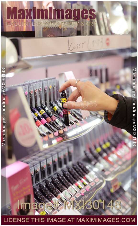 Woman taking lip gloss lipstick tester in a Japanese makeup store