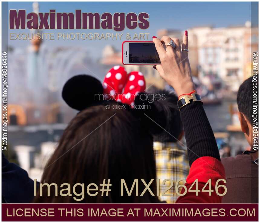 Woman taking pictures with iPhone of show at Tokyo Disneysea