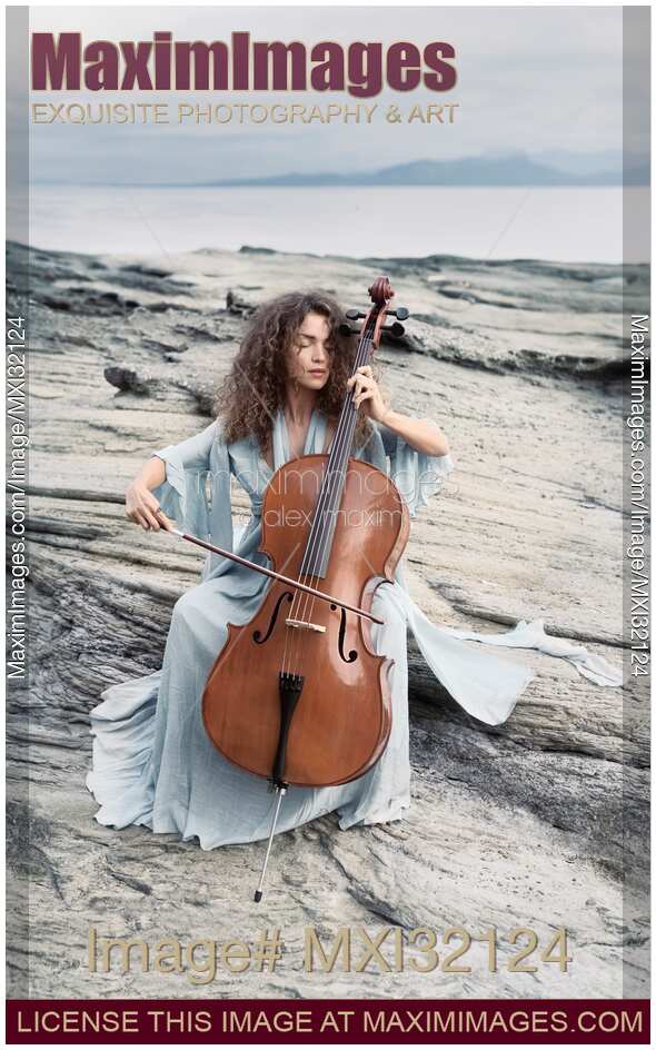 Woman thoughtfully playing cello on an ocean shore in sunrise scenery