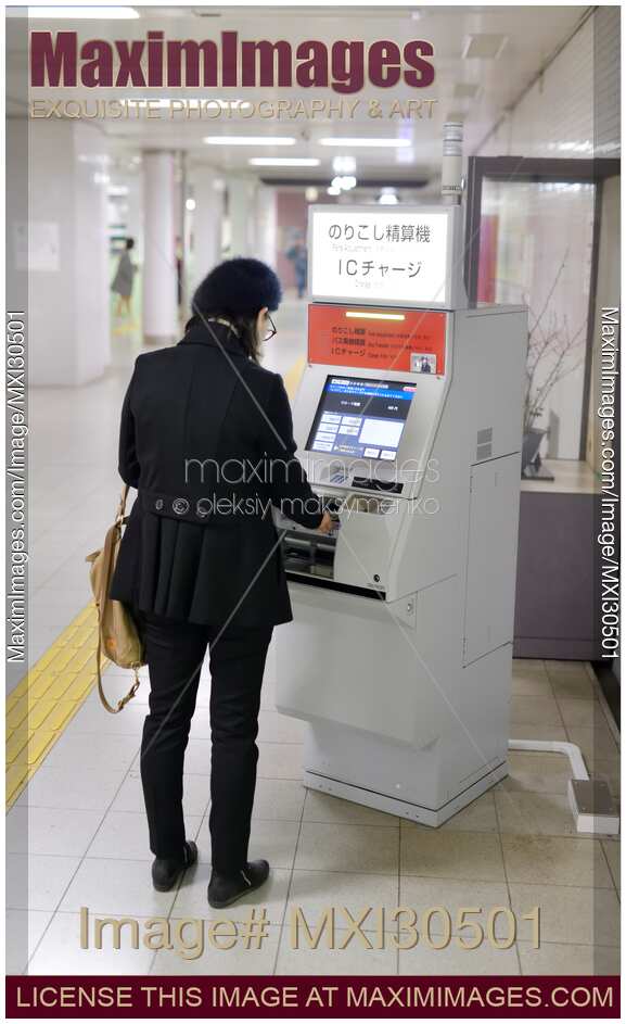 Woman using a fare adjustment machine at a subway station in Japan