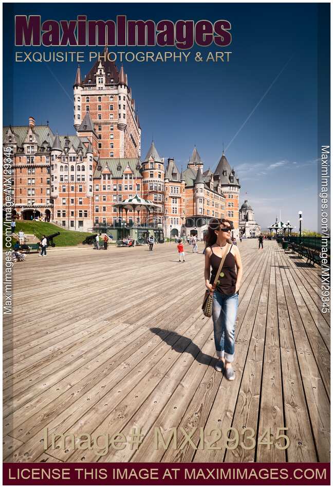 Woman walking on Dufferin terrace by the Fairmont Le Chateau Frontenac castle in old Quebec city