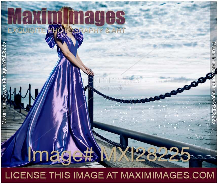 Woman wearing beautiful long blue dress standing at waterfront