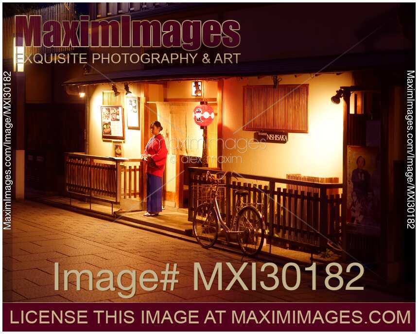Woman welcoms guests by the entrance of traditional Japanese restaurant Nishisaka at night in Gion Kyoto