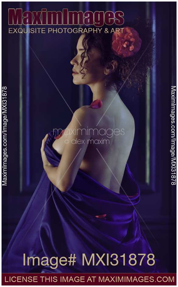 Woman with a flower in her hair sitting with her naked body wrapped in bed sheets revealing bare back