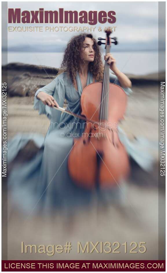 Woman with a nostalgic look playing cello on a sea shore in sunrise scenery
