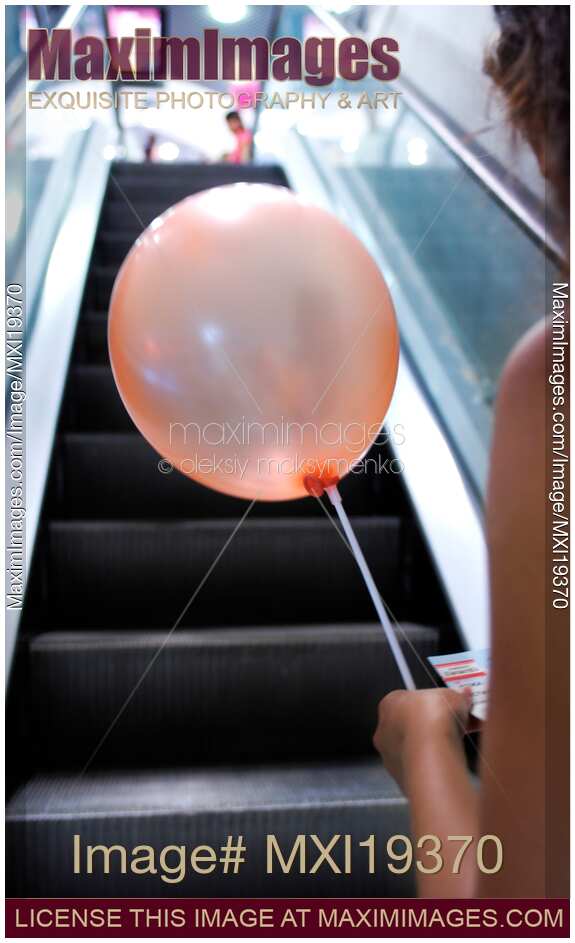 Woman with balloon on escalator