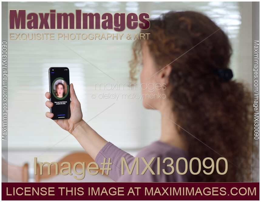 Woman with iPhone X setting up Face ID biometric authentication