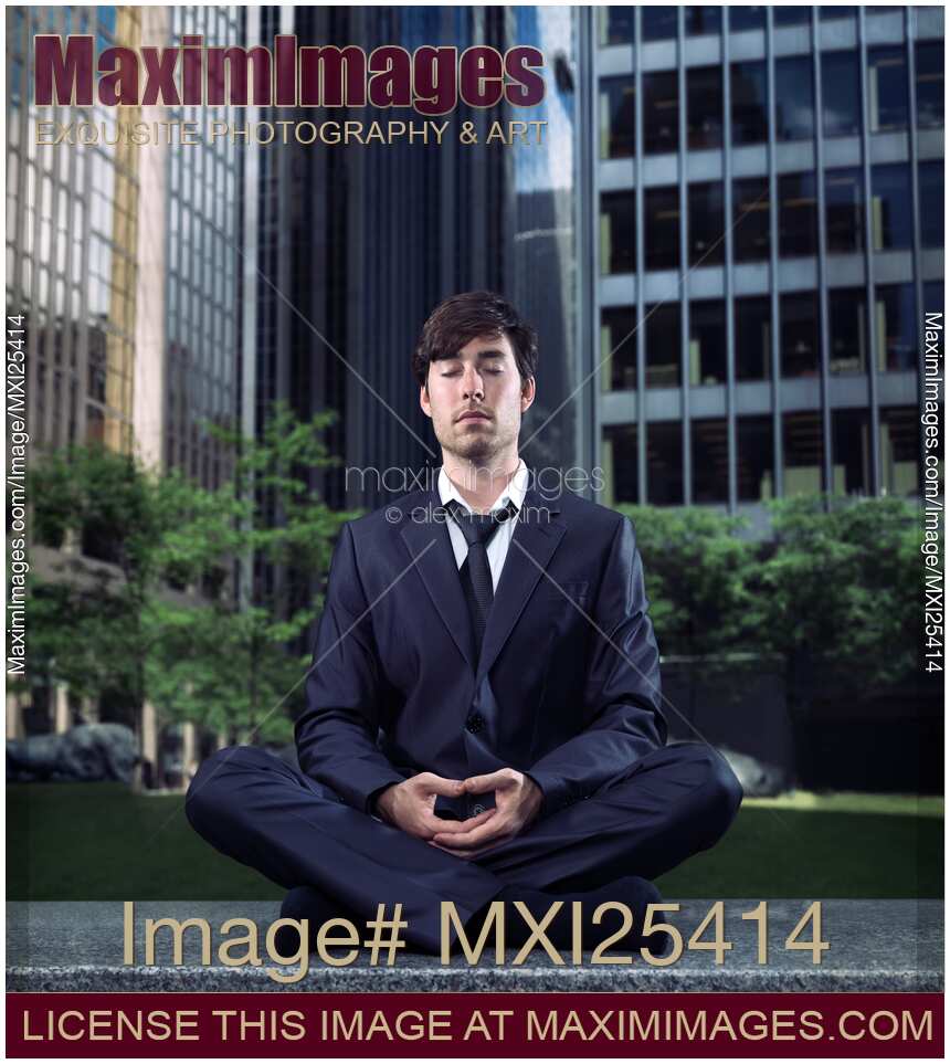 Young businessman meditating in city downtown