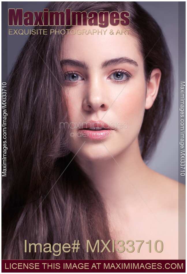 Young caucasian woman beautiful face with large gray eyes, sensual pink lips and long brown hair. Studio beauty portrait.