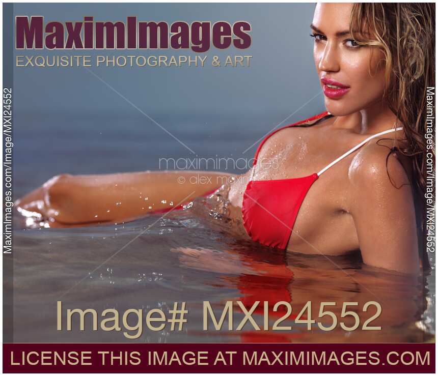 Young glamorous woman in red bikini lying in water
