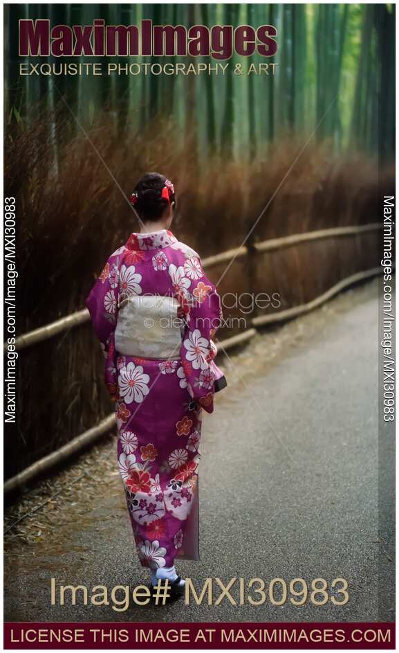 Young Japanese woman in kimino walking along Arashiyama bamboo forest in Kyoto