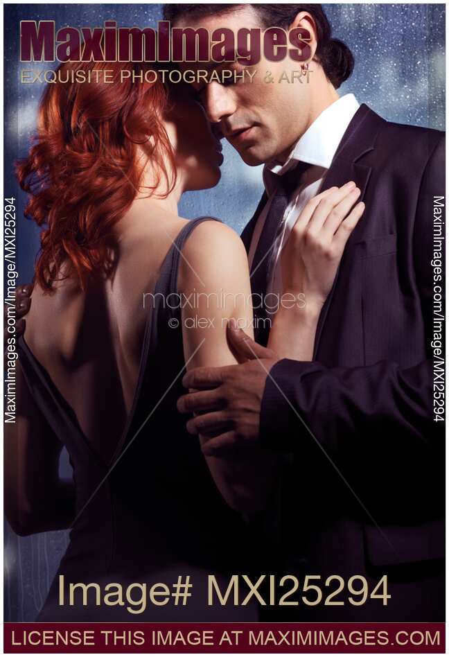 Young man and woman embracing in front of window