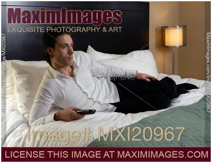 Young Man Lying on a Bed and Watching TV