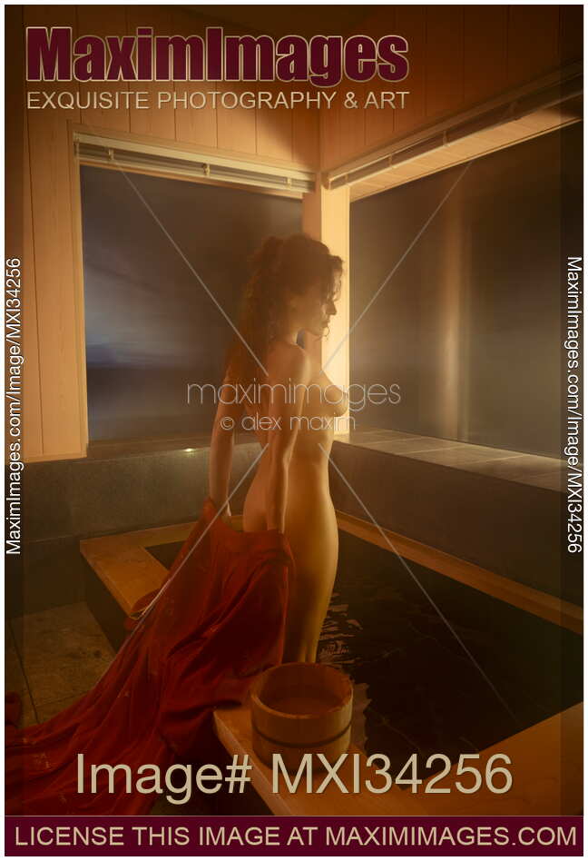Young nude woman undressing entering naked into a steamy indoor onsen bath tub