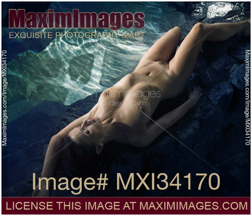 Young nude woman with beautiful wet sexy naked body lying on rocks by an onsen hot spring bath