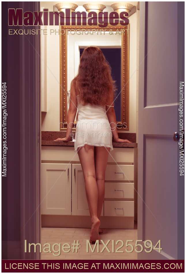 Young sexy woman at a bathroom mirror