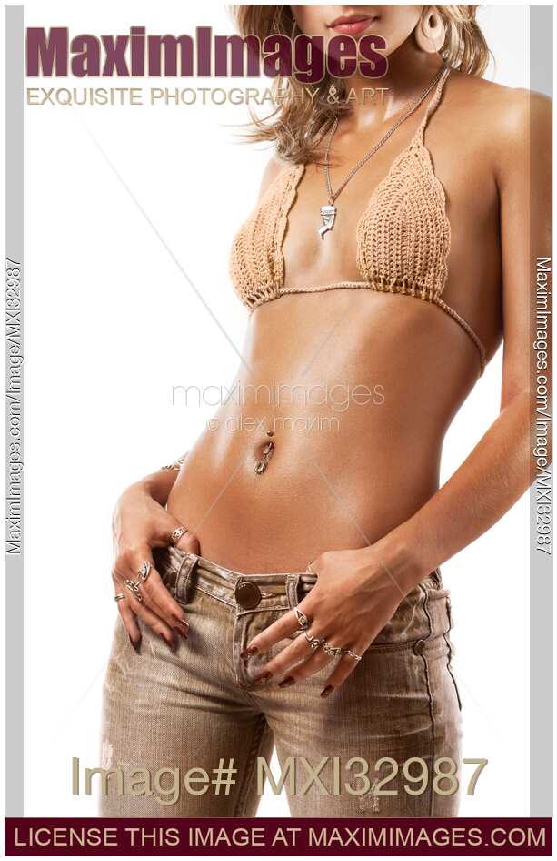 Young sexy woman with shiny tanned skin in low rise jeans and knit bikini top