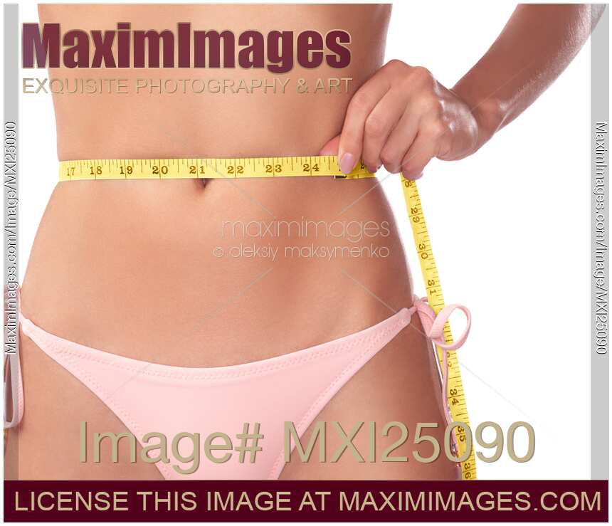 Photo of Young slim woman measuring her waist with a tape