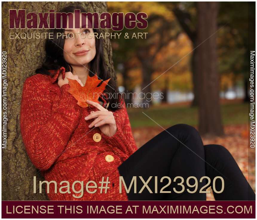 Young Smiling Woman Cuddling in a Sweater in Autumn