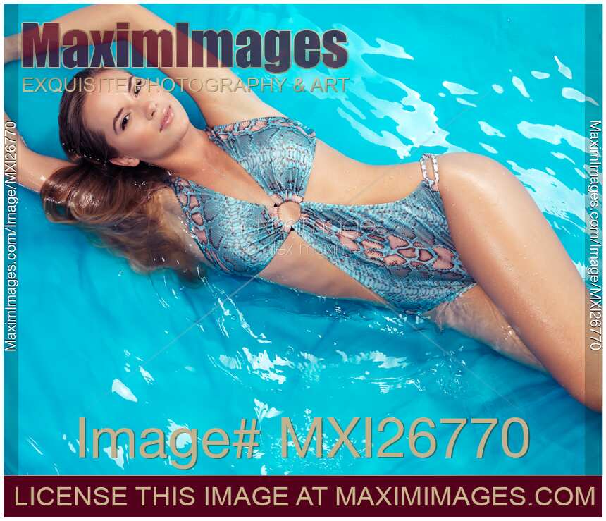 Young smiling woman in swimsuit lying in blue water