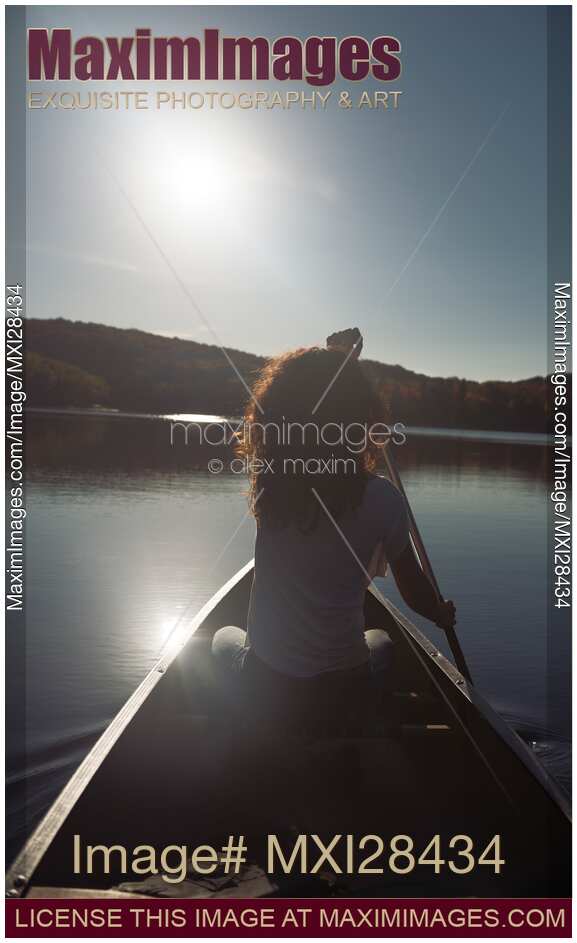 Young woman canoeing on a lake lin sunlight