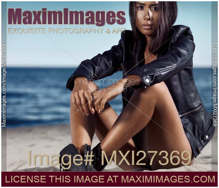 Young woman in black leather jacket sitting at the beach