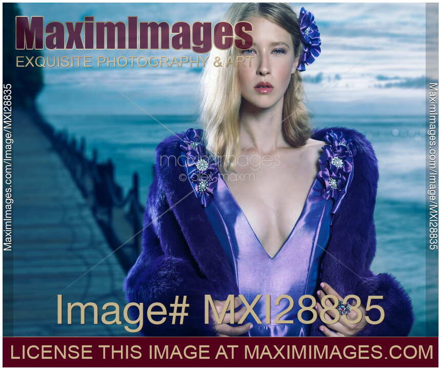 Young woman in blue dress and fur coat at waterfront