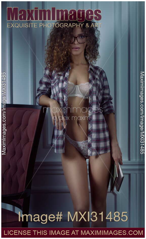 Young woman in glasses standing with a book and open shirt revealing lingerie on her sexy body