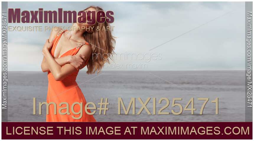 Young woman in orange dress standing on a shore